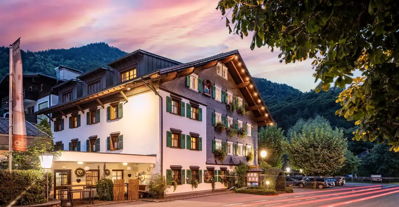 Das Hotel Adler am Abend mit beleuchteten Fenstern unter rosa Himmel